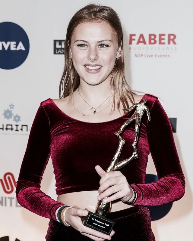 Susan Radder in a maroon velvet crop top holding a trophy.